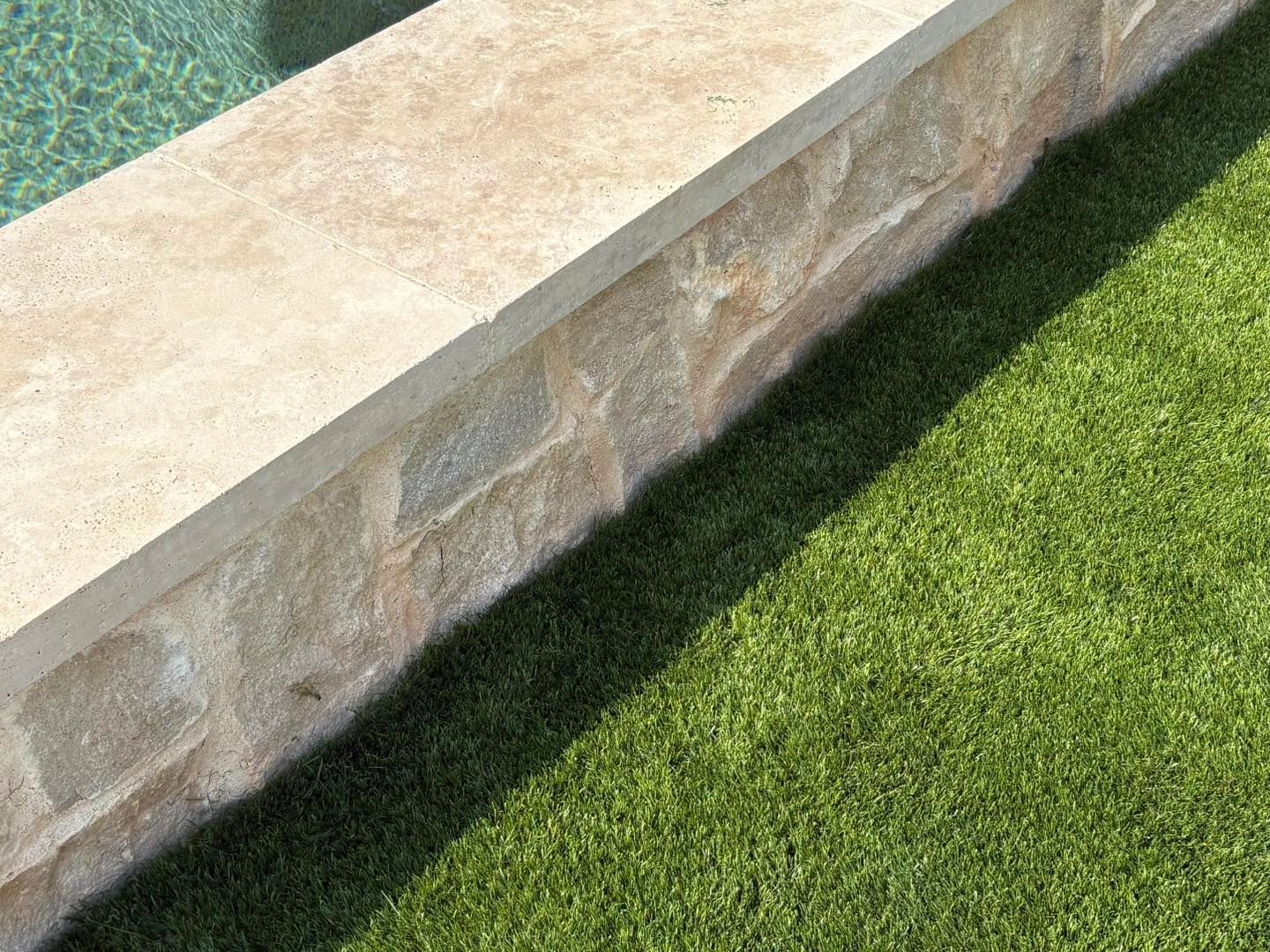 Turf meeting natural stone pool coping, clean edge detail